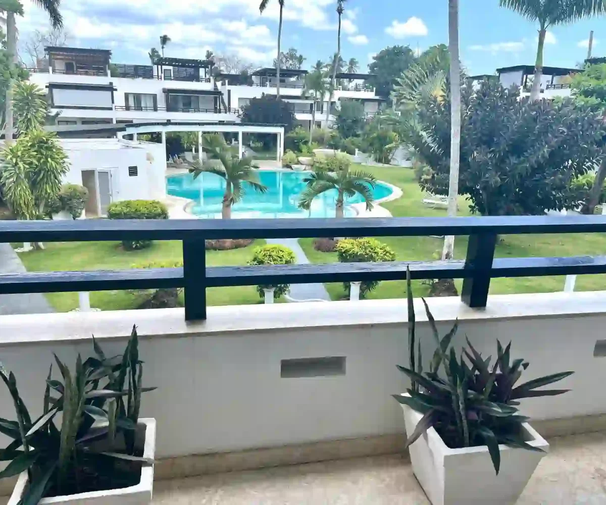 Vista desde el balcón del apartamento en Aligio Las Terrenas mostrando la piscina, jardín y edificio cercano