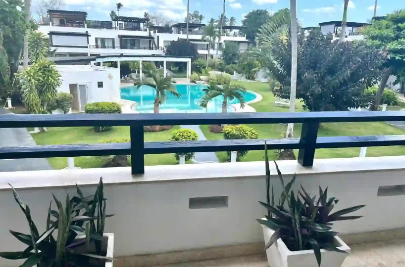 Vista desde el balcón del apartamento en Aligio Las Terrenas mostrando la piscina, jardín y edificio cercano