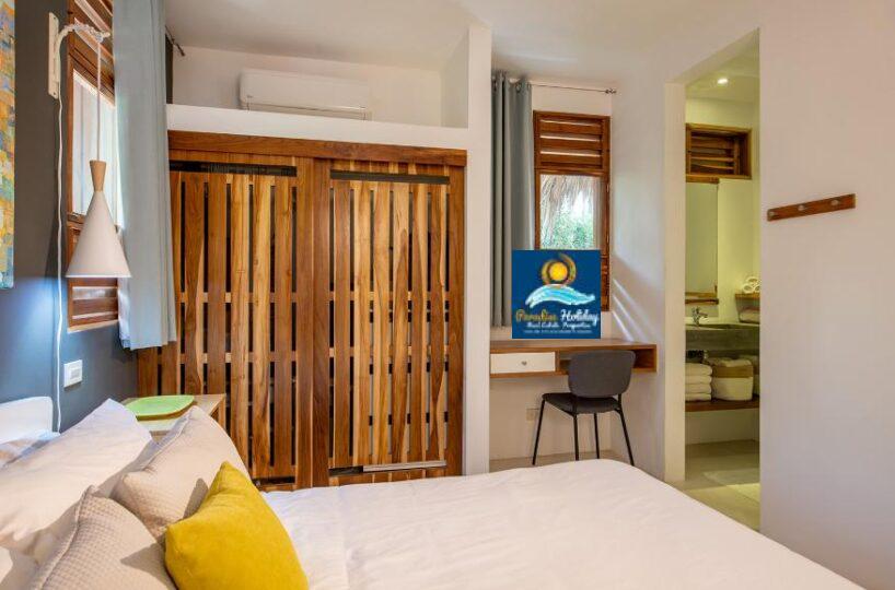 Amplio dormitorio con mobiliario moderno y zonas naturales.