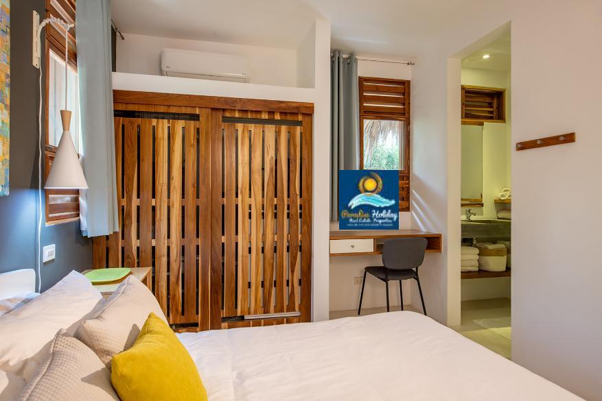 Amplio dormitorio con mobiliario moderno y zonas naturales.