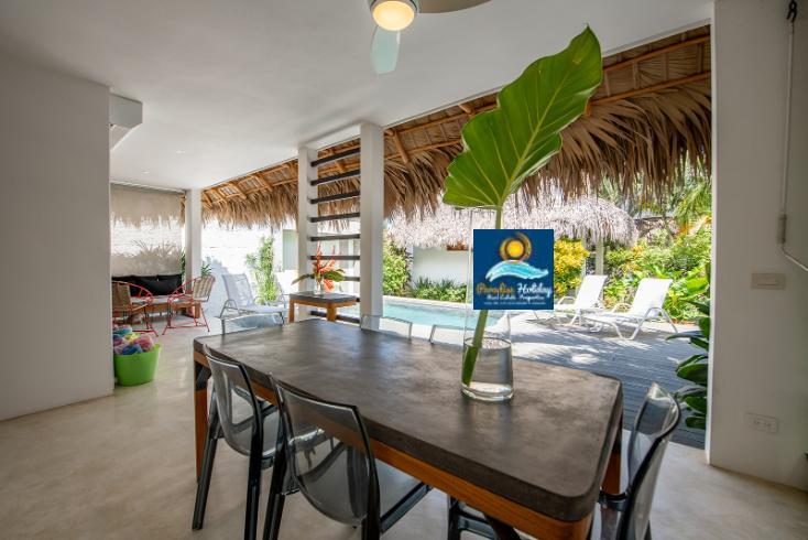 Paredes blancas, muebles modernos y vista a la piscina y jardines tropicales en Santa Domingo.