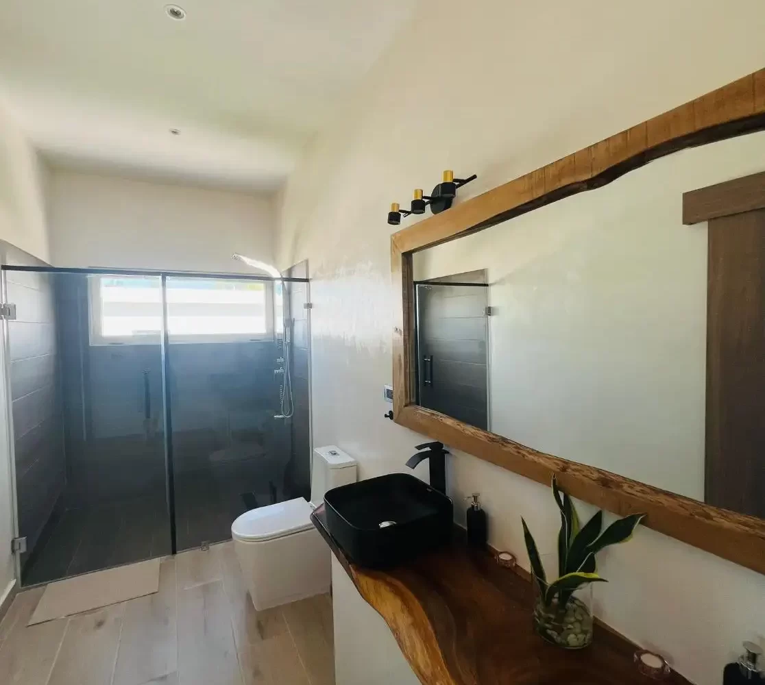 Baño completo con espejo, lavadero, inodoro y ducha en villa de Las Terrenas