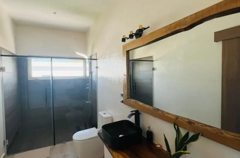 Baño completo con espejo, lavadero, inodoro y ducha en villa de Las Terrenas