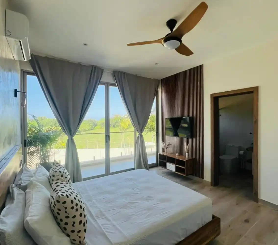 habitación con cama, TV, baño y balcón en villa Las Terrenas
