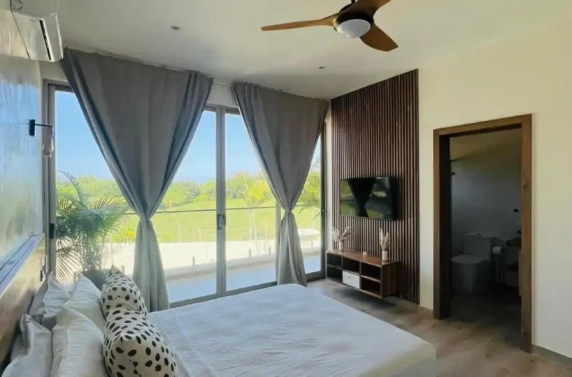 habitación con cama, TV, baño y balcón en villa Las Terrenas