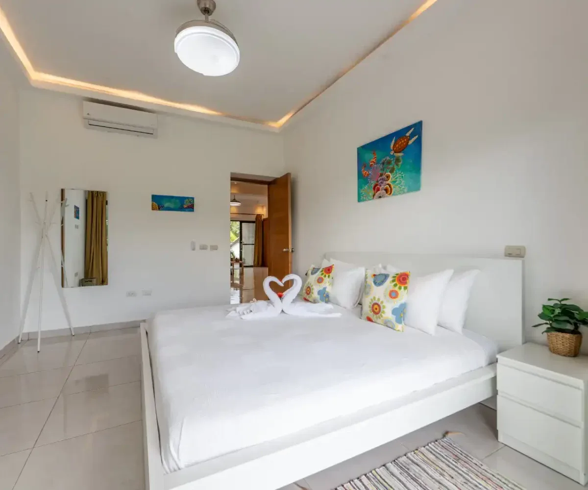 Habitación luminosa con cama doble, decorada con cojines coloridos y detalles modernos.