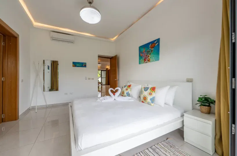 Habitación luminosa con cama doble, decorada con cojines coloridos y detalles modernos.