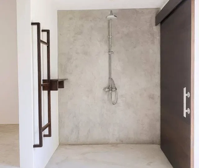Amplio baño con ducha moderna y paredes de concreto en Las Terrenas. Ideal para apartamentos cerca d.