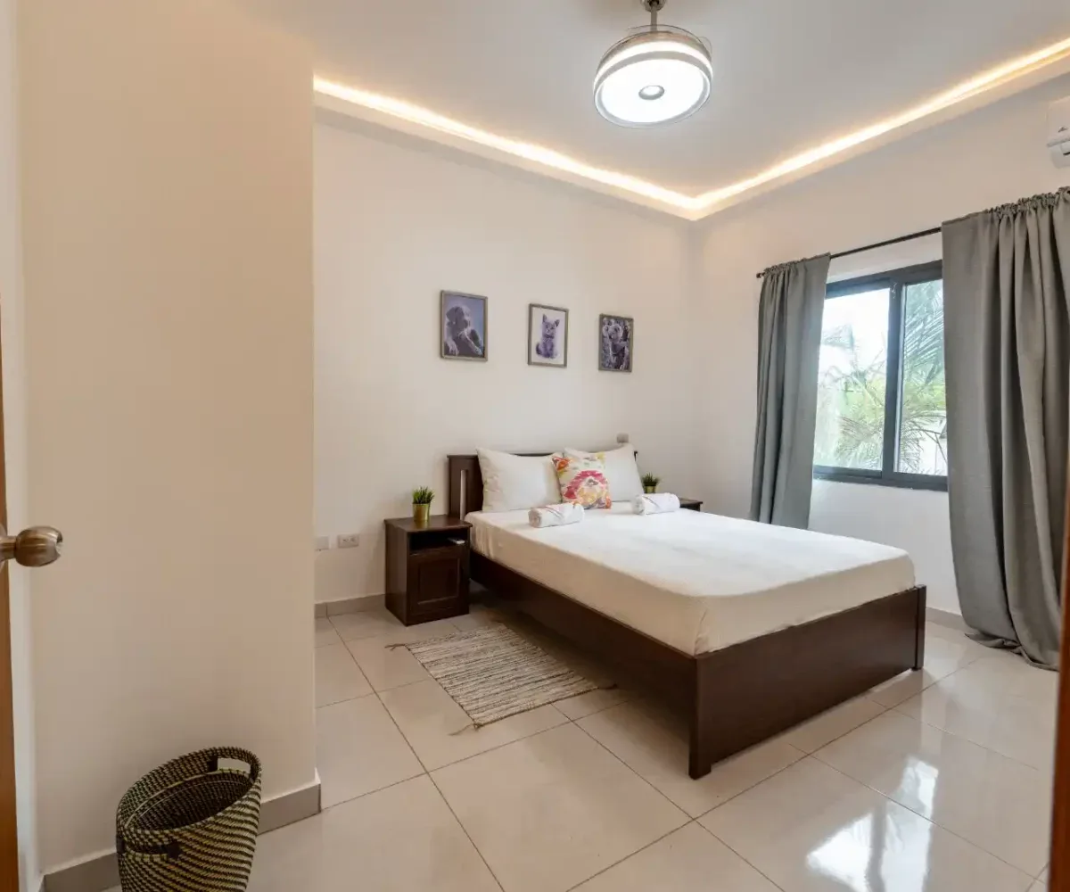 Habitación espaciosa con cama doble, decorada con arte en la pared y cortinas gris en Las Terrenas.
