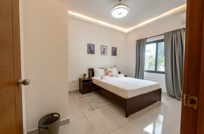 Habitación espaciosa con cama doble, decorada con arte en la pared y cortinas gris en Las Terrenas.